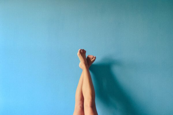 twee benen met de voeten omhoog steunen tegen een blauwe muur.